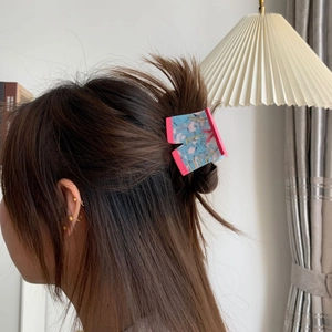 Detail of marble pattern acetate hair claw clip worn on a messy bun with golden accents