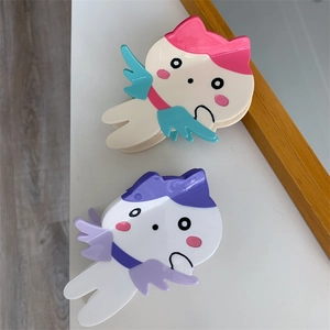Detail süßer Katzen-Haarklammern mit kleinen Flügeln in Pink-Blau und Violett-Tönen