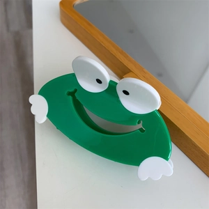 Detailed view of a cute green frog-shaped hair claw clip with a glossy acetate finish