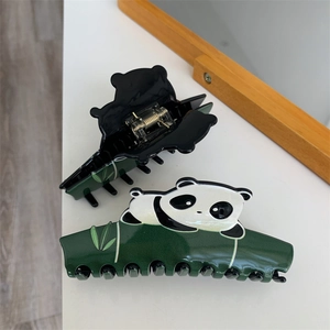 Close-up of cute cartoon panda and bamboo shark hair clip with metal spring detail