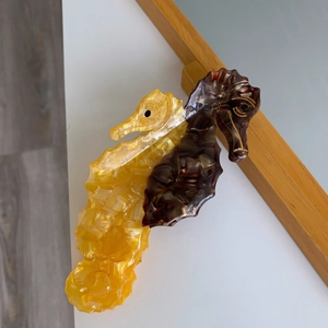 Detail view of yellow and brown seahorse hair claw clip with acetate marble texture