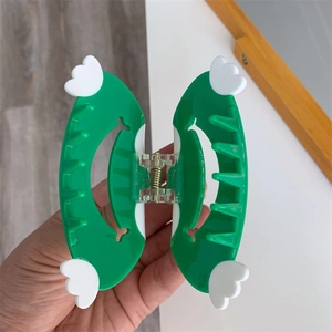 Detail view of a bright green acetic acid hair claw clip with white wing accents