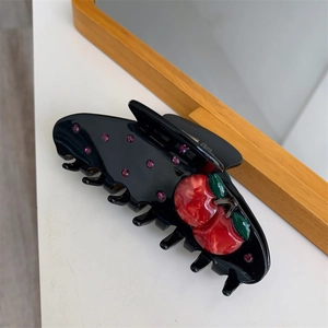 Detail of black shark hair claw with 3D red cherries and purple rhinestones