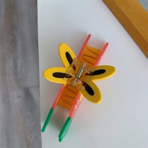 Detailed top view of a colorful butterfly hair claw clip with vibrant orange and yellow tones