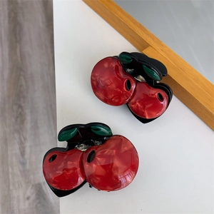 Detailed close-up of double cherry hair claw clips with marble texture and green leaves