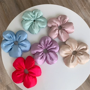 Set of six colorful satin flower hair scrunchies with elegant metallic luster on white stand