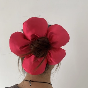 Macro view of oversized red fabric flower scrunchie accessory worn on hair bun