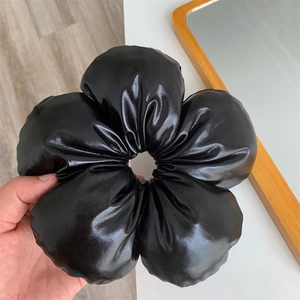 Détail de l'élastique à cheveux fleur en simili cuir noir avec finition brillante