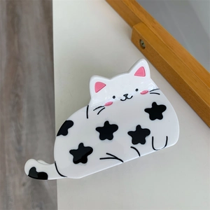 Detail einer weißen Haarklammer in Katzenform mit niedlichem schwarzem Sternmuster