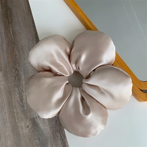 Detail of a oversized champagne satin floral scrunchie with soft petal-like silk texture