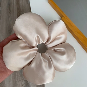 Detail of a large champagne satin flower hair scrunchie with a glossy silk texture