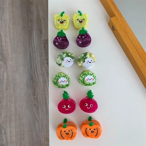 Vista plana de pinzas para el cabello de acetato con formas de verduras como calabaza