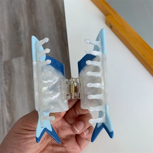 Detailansicht der blau-weißen Haarklammer aus Acetat in Haifischflossen-Form mit Feder