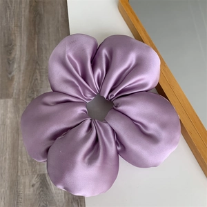 Detailed view of the large purple satin flower scrunchie with silky fabric textures