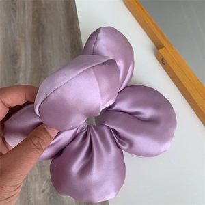 Detailed close-up of a large lilac satin scrunchie with layered 3D floral petal design