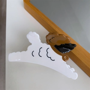 Detail einer weißen Hunde-Haarklammer aus Acetat auf einem minimalistischen Holztisch