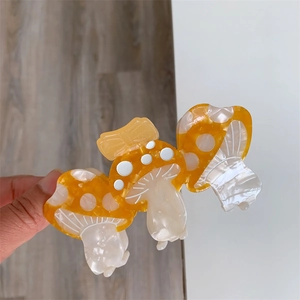Vista dettagliata di tre mollette per capelli a fungo in acetato lucido crema e arancio