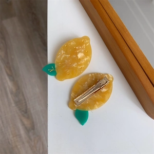 Détail des pinces à cheveux en acétate en forme de citron avec texture marbre jaune