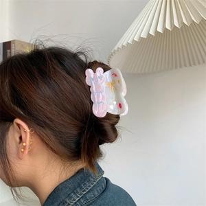 Vista detallada de la pinza de mariposa rosa con orejas de conejo en el cabello de la modelo
