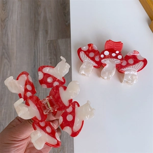 Dettaglio della pinza per capelli a forma di fungo rosso a pois con molla di apertura