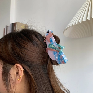 Macro side view of acetate grasshopper hair claw clip worn on head with pastel patterns