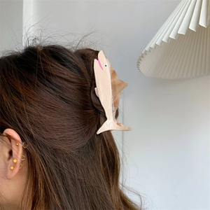 Detail showing marble textured shark hair claw clip worn on long brown hair