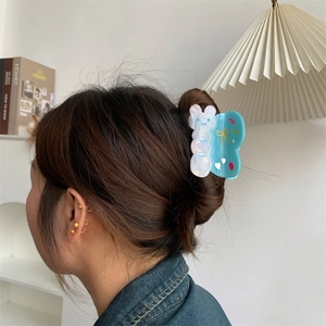 Detalle de una pinza para el cabello de acetato azul y blanca con forma de mariposa