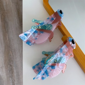 Detail view of two butterfly hair claws with marble texture in pink, blue, and green tones