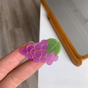 Détail d'une pince à cheveux raisin violet avec feuilles vertes et liserés dorés