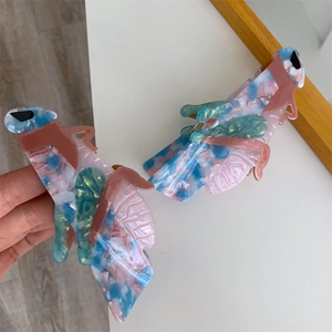 Detailed view of large cicada-shaped acetate hair claws with colorful marble textures