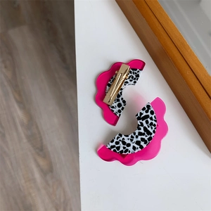 Détail de barrettes en acétate rose à motif léopard avec pinces bec de canard dorées