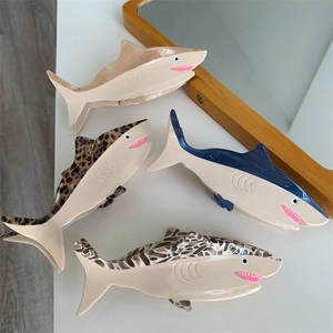 Set of four unique shark-shaped hair claws in various patterns on a clean white surface