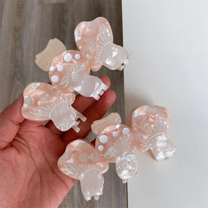 Dettaglio di fermagli a fungo in acetato rosa perlato con puntini bianchi decorativi