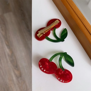 Détail des pinces à cheveux cerise en acétate avec strass et attache métallique