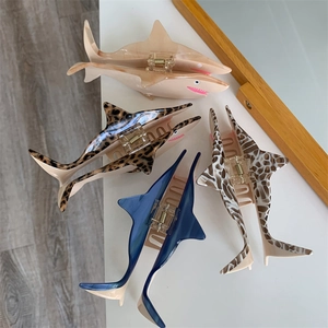 Detailed close-up of shark-shaped hair claws in four colors on a white tabletop