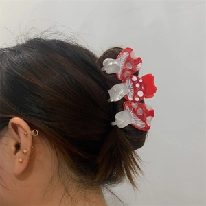 Tre pinze per capelli a forma di fungo rosso con pois bianchi su capelli scuri