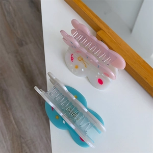 Detalle de dos pinzas para el cabello de acetato con patrones de estrellas y ondas