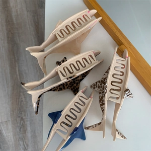 Detail view of four shark-shaped acetate hair clips in leopard and solid blue colors