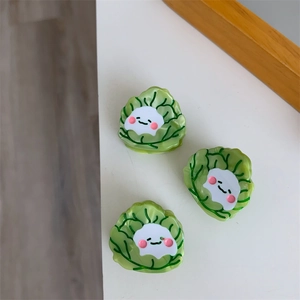 Detalle de tres creativas pinzas para el cabello de acetato en forma de col con caritas