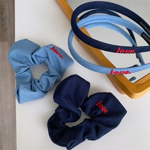Blue denim headband and scrunchie set featuring red love embroidery in a flat lay view