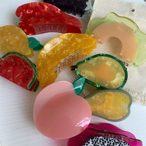 Détail de pinces à cheveux en acétate colorées en forme de fruits comme pêche et pastèque