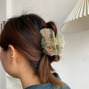 Detailed view of iridescent seashell hair claw clip with colorful texture in hair