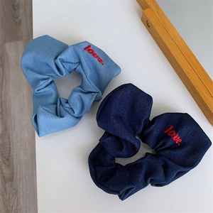 Close-up of denim scrunchies in light and dark blue with red love embroidery detail