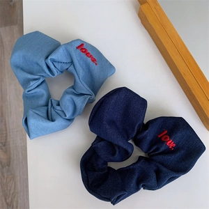 Close-up of denim scrunchies featuring red love embroidery in light and dark blue