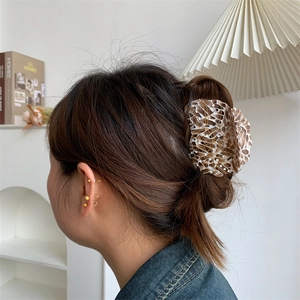 Close-up of marble texture acetate hair claw with golden woven wire detail on model
