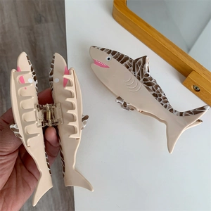 Detail showing the internal metal spring and serrated teeth of the shark hair clip