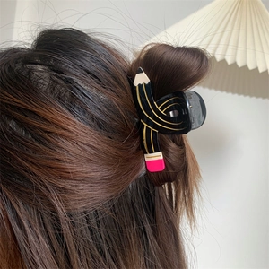 Detail of creative pencil-shaped hair claw clip holding hair in a stylish half-up style
