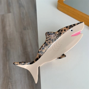 Detail of shark-shaped acetate hair claw clip featuring tortoiseshell and cream patchwork