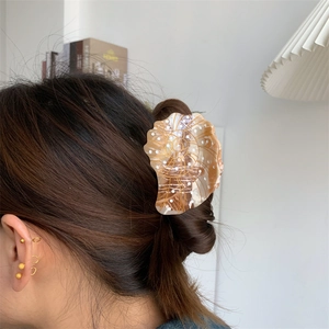 Shell-shaped acetate hair claw clip with tortoiseshell texture and gold accents for women