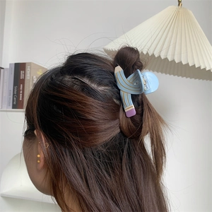 Detail of light blue creative pencil shaped hair claw clip in a half-up hairstyle